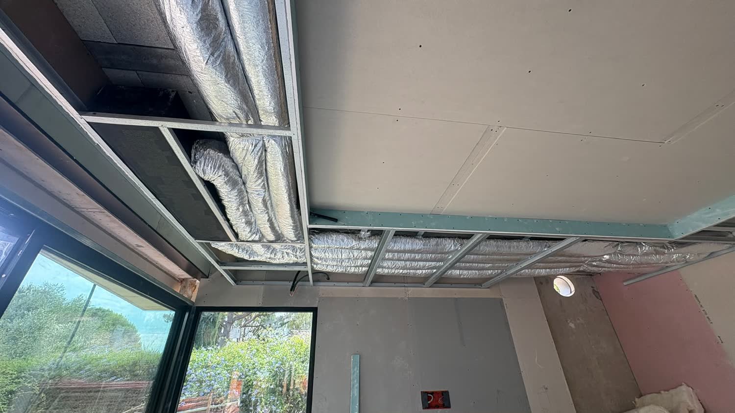 Climatisation gainable encastrée dans un faux-plafond au-dessus d'une baie vitrée