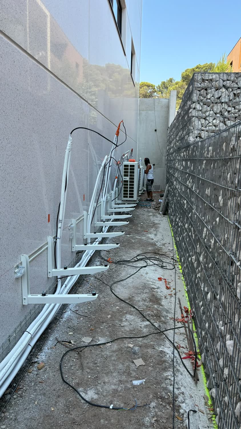 Groupes extérieurs de climatisation en cours de pose sur supports muraux